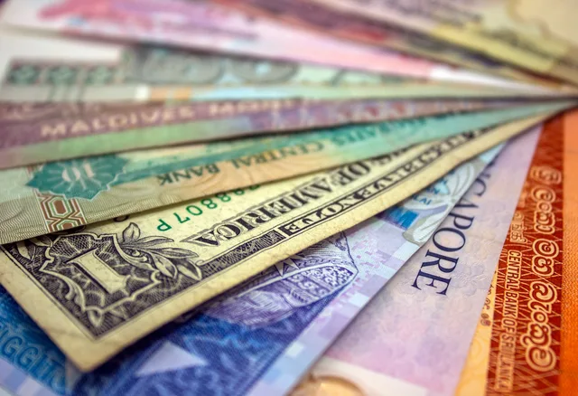 A close-up view of various international banknotes showcasing diverse currencies. Comparing transaction and reporting currencies