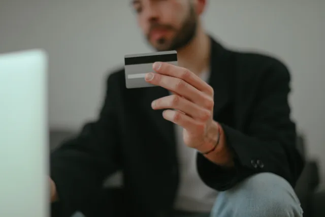 Blurred image of a man holding a credit card, emphasizing online shopping. Connecting ecommerce settlements to bookkeeping